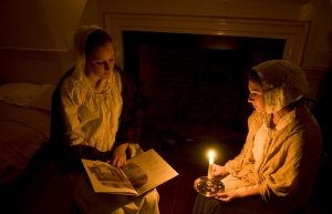 Two girls reading by candlelight.