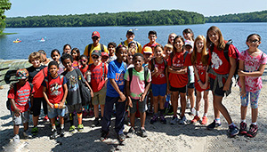 Group of children standing beside a lake.