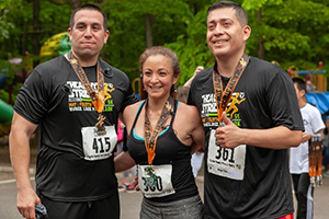 Two men and a woman race runners with medals.