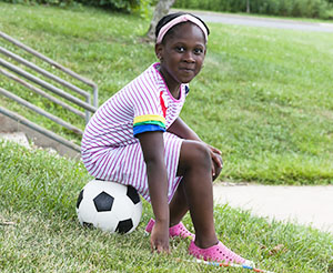 Girl sitting on a soccer ball.