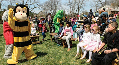 Bee mascot and children sitting on benches.