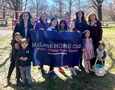 McLean MOMs Club banner held by women and children.
