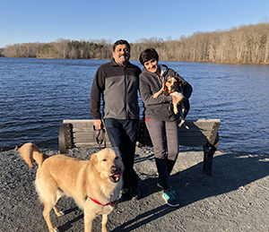 Two people with two dogs by a lake.