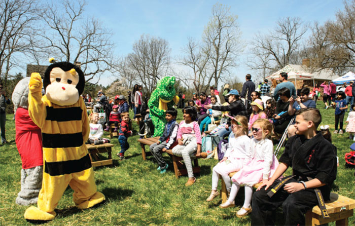 Person in bee costume and audience sitting on benches.